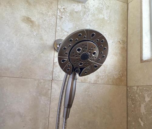a shower with a shower head on a wall at Holiday Surf Hotel (with full kitchen) in Honolulu