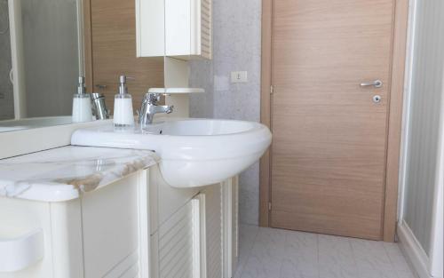 a bathroom with a white sink and a wooden door at Michelangelo Apartment in Civitavecchia