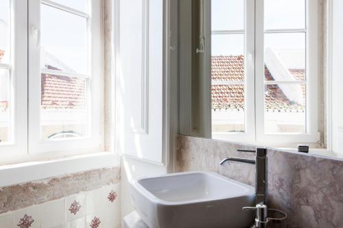 a bathroom with a sink and two windows at Alfama Sophisticate Flat With Balconies 2Bedrs 2Baths & AC in 19th Century Building Historic Center in Lisbon