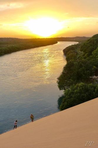 two people standing on the shore of a river at sunset at Pousada kaz'oca in Icaraí