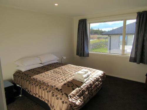 a bedroom with a bed and a large window at Tesoro in Lake Tekapo