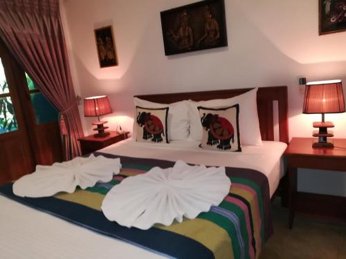 a bedroom with a bed with white sheets and pillows at The Nature Park Villa in Sigiriya