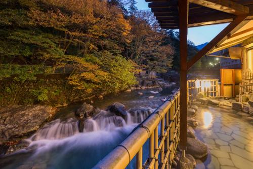 a view of a waterfall next to a river at Shima-Onsen Toshimaya in Nakanojo