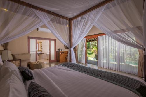 Un dormitorio con una cama grande con dosel. en ILA Villa Ubud, en Ubud