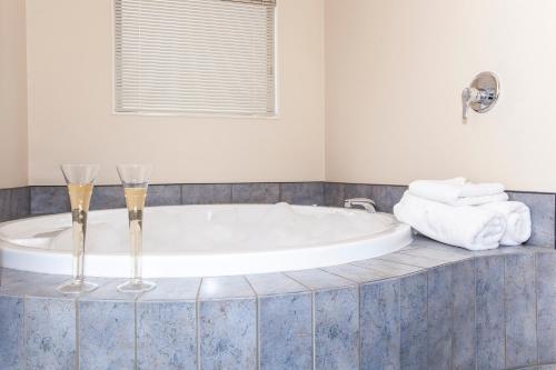 a bathroom with a tub with two champagne glasses at Te Mata Lodge in Havelock North