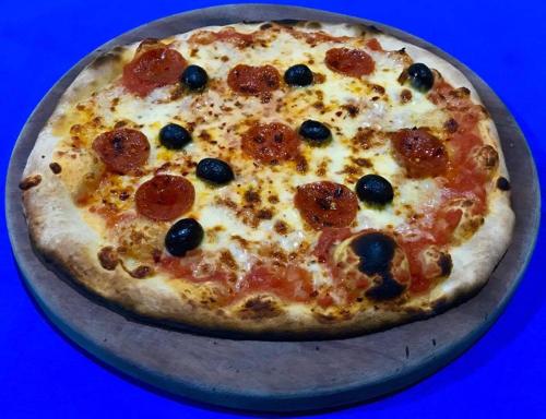 a pizza with pepperoni and olives on a pan at Club Surf Popoyo in Popoyo