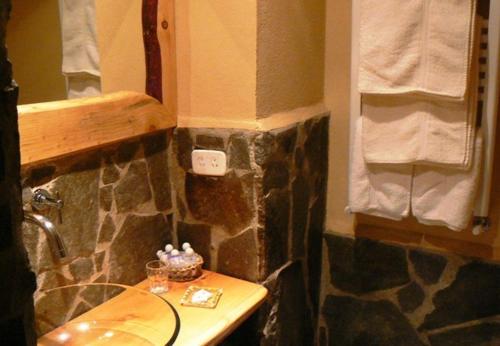 baño con lavabo y pared de piedra en Ruca Pehuen Eco-Lodge De Montaña en Caviahue