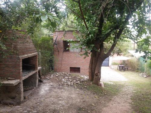 un edificio de ladrillo con un árbol delante de él en Cabaña San Pablo en San Salvador de Jujuy