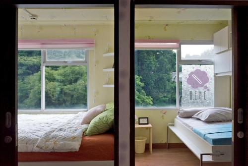 a bedroom with a bed and two windows at Bene Room at Jarrdin Cihampelas in Bandung