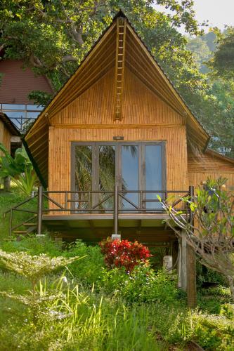 a small wooden house with a porch and some flowers at The Cove Phi Phi in Phi Phi Don