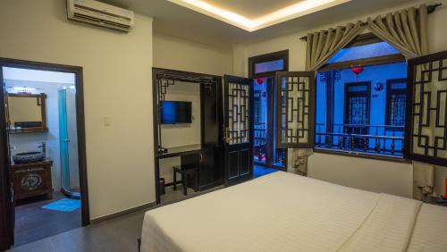 a bedroom with a bed and a television and windows at Phu House in Phu Quoc
