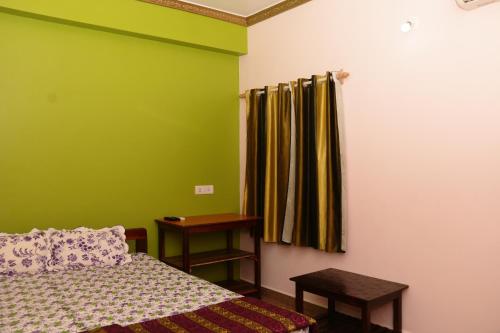 a bedroom with a bed and a green wall at Sai Guru Guest House in Anjuna
