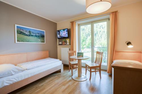 a bedroom with a bed and a table and a window at JUFA Hotel Veitsch in Veitsch