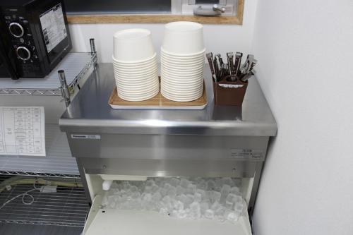 a pile of plates on a shelf with a stack of cups at Nikko Station Hotel 2 in Nikko