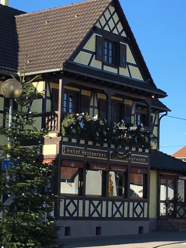 a black and white building with flowers in windows at Hôtel-Restaurant A La Couronne in Kilstett