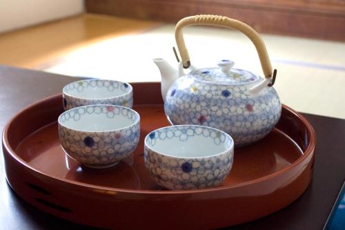 a tray with four cups and a tea pot on it at Tsukiji Hostel Wakayama 1 in Wakayama