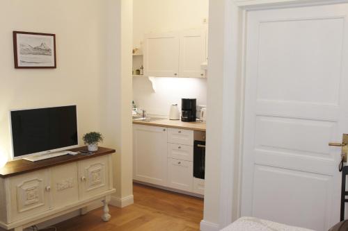 uma cozinha com armários brancos e uma televisão numa mesa em Apartment Creme zentral em Bremen
