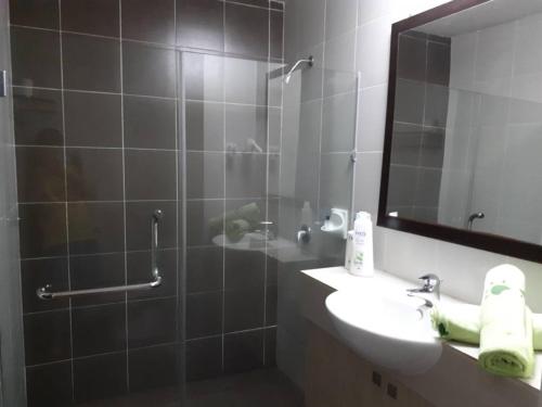 新山的住宿－巴余海濱度假村（一室公寓民宿），浴室配有盥洗盆和带镜子的淋浴