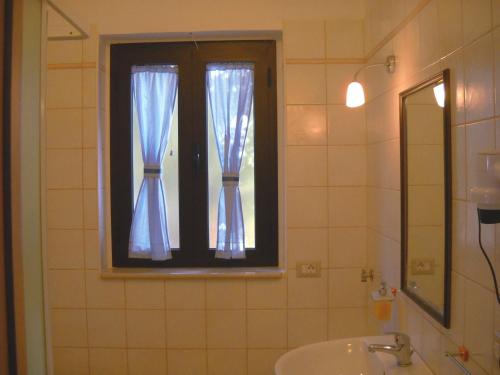 a bathroom with a sink and a window with blue curtains at Zagare Residence in Rodi Garganico