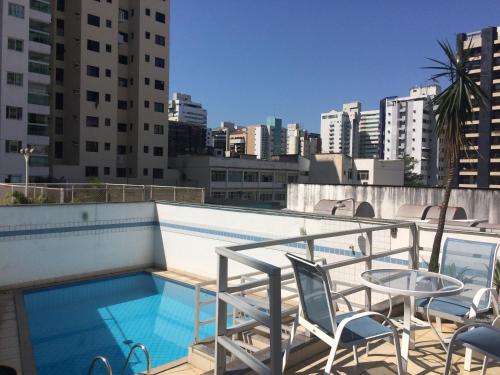 una piscina en la azotea de un edificio con sillas y mesa en Apart Quartier Latin en Vitória