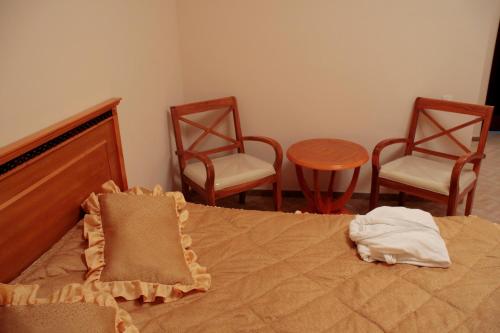 a bedroom with a bed with two chairs and a table at Flamingo in Aktobe