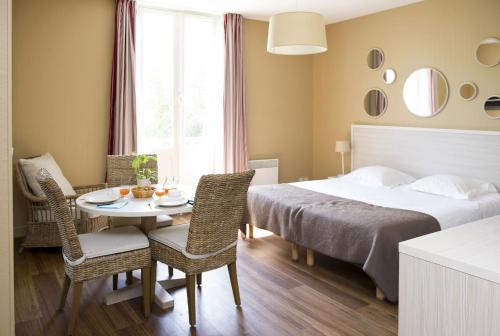 - une chambre avec un lit, une table et des chaises dans l'établissement Résidence de Tourisme Vacances Bleues Villa Regina, à Arcachon