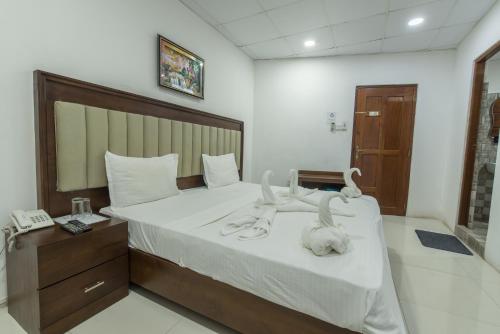 Schlafzimmer mit einem Bett mit weißer Bettwäsche und einem Telefon in der Unterkunft Metro City Hotel in Colombo