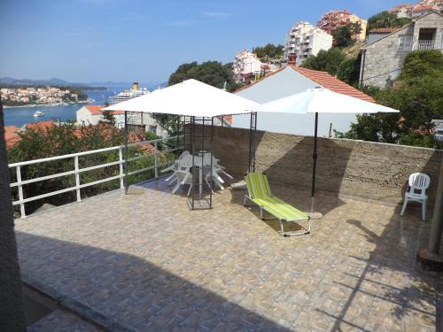 a patio with two white umbrellas and a table and chairs at Apartments & Rooms Abba in Dubrovnik