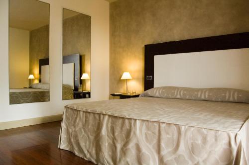 a bedroom with a large bed and two mirrors at Cremona Palace Hotel in Costa Santʼ Abramo