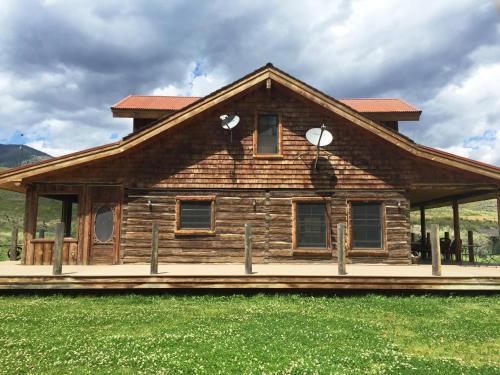 a log cabin with a porch in a field at Schoolhouse Cabin in Gardiner