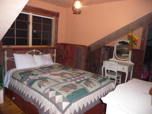 a bedroom with a bed and a desk with a mirror at Schoolhouse Cabin in Gardiner