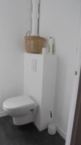 - une salle de bains blanche avec des toilettes et un panier dans l'établissement Le P'tit Appart De l'Orme, à Saint-Malo
