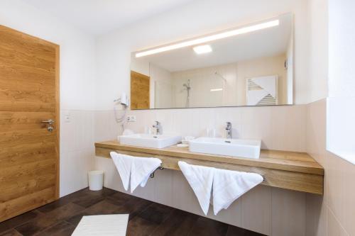 a bathroom with two sinks and a mirror at Apart Madeleine Superior inklusive Summercard in Sölden