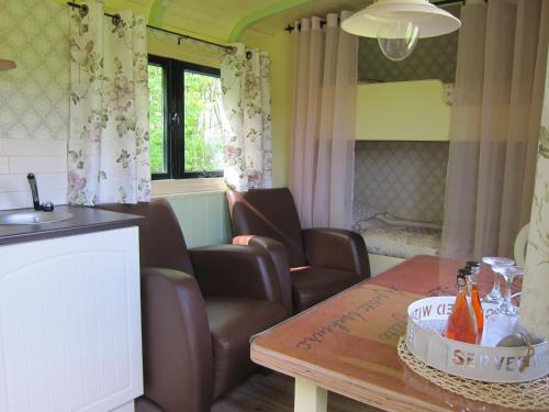 salon z 2 krzesłami i stołem w obiekcie Pipowagen Minicamping De Linde w mieście Merselo