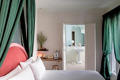 
a bedroom with a white bed and white curtains at Hotel des Grands Boulevards in Paris
