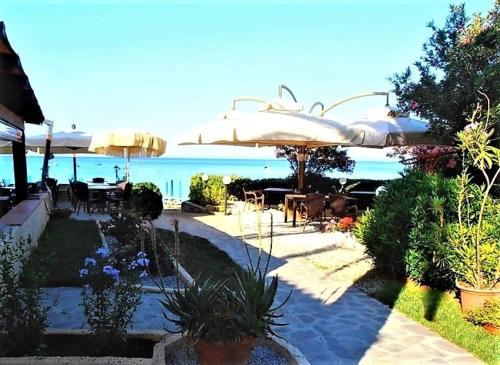 a patio with tables and umbrellas and the ocean at Albatros in Capoliveri