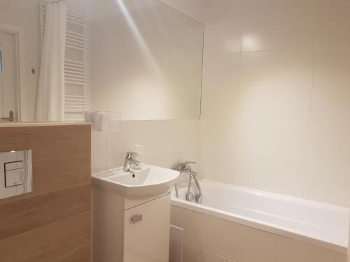 a white bathroom with a sink and a bath tub at Hennela Apartment in Warsaw