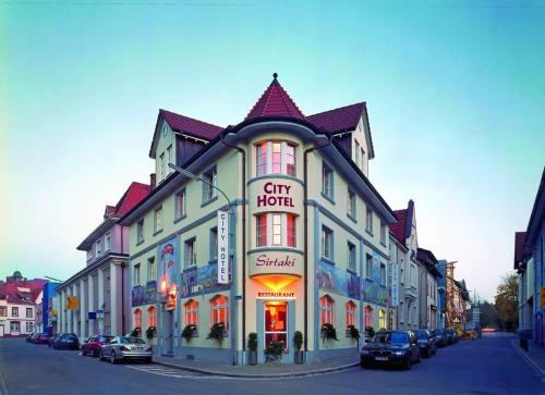 a large white building with a sign on a street at City Hotel in Schopfheim