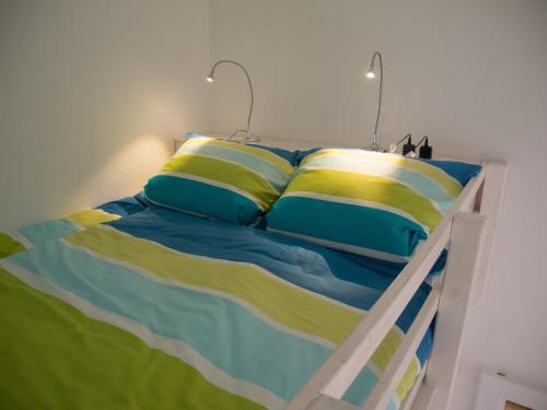 łóżko z niebieską i żółtą pościelą i poduszkami w obiekcie Apartment Türkis zentral w Bremie