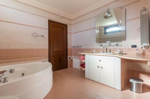 a bathroom with a tub and a sink and a bath tub at Anaelehouserooms LTB in Arborea 