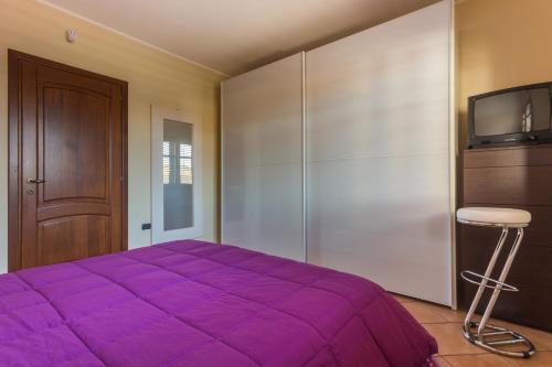 a bedroom with a purple bed and a tv at Anaelehouserooms LTB in Arborea 