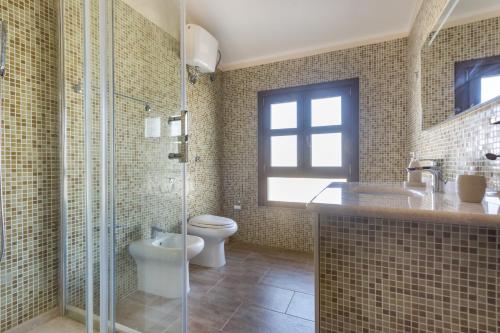 a bathroom with a toilet and a glass shower at Anaelehouserooms LTB in Arborea 