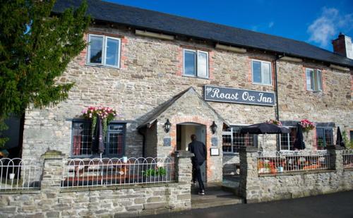 Un uomo in piedi sulla porta di un edificio di mattoni di The Roast Ox Inn a Builth Wells