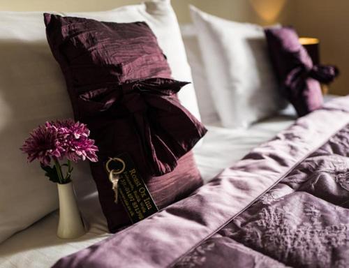 a bed with purple pillows and a vase with flowers at The Roast Ox Inn in Builth Wells