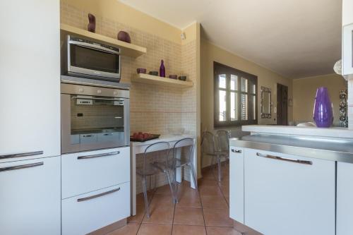 a kitchen with white appliances and a table with chairs at Anaelehouserooms LTB in Arborea 