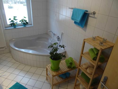 オスターホルツ・シャルムベックにあるHof Sonnengoldのバスルーム(バスタブ、鉢植えの植物付)
