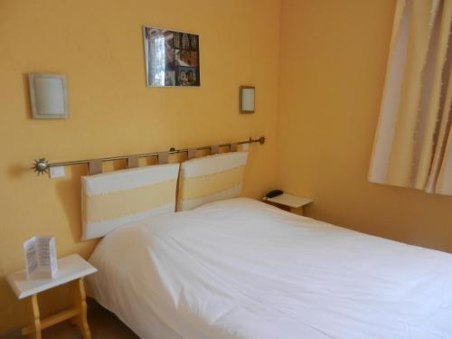 a bedroom with a white bed in a room at Logis Auberge De La Plaine in La Rothière