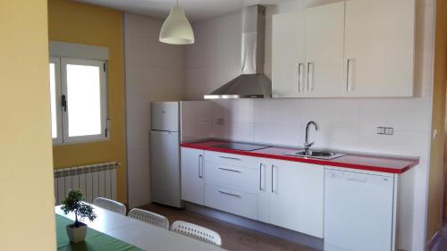 eine Küche mit weißen Schränken und einer roten Arbeitsplatte in der Unterkunft Camino del Morisco in Caminomorisco
