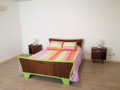 a bedroom with a bed with a colorful bedspread and two tables at Pés Verdes-Alojamento e Chá in Ponta Delgada