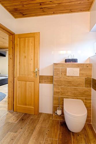 a bathroom with a toilet and a wooden door at Vila Sekvoj in Harrachov